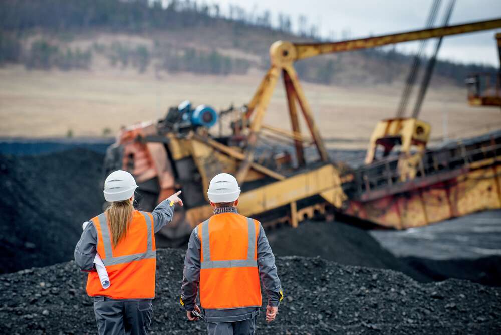 construction workers in safety vests and helmets looking at a large construction vehicle